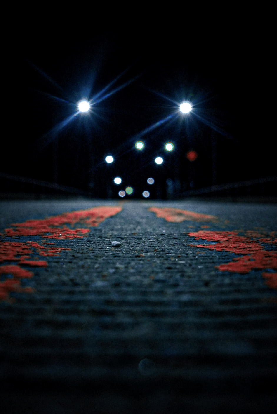 Low-angle headlights on a cracked night road